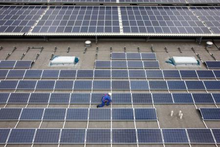 A stock image of photovoltaic panels on the roof of a large warehouse